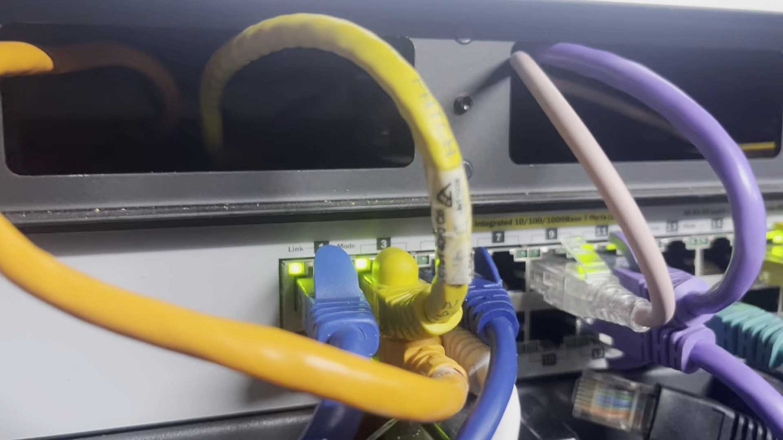 Close-up of a home lab network switch with colour-coded ethernet cabling.