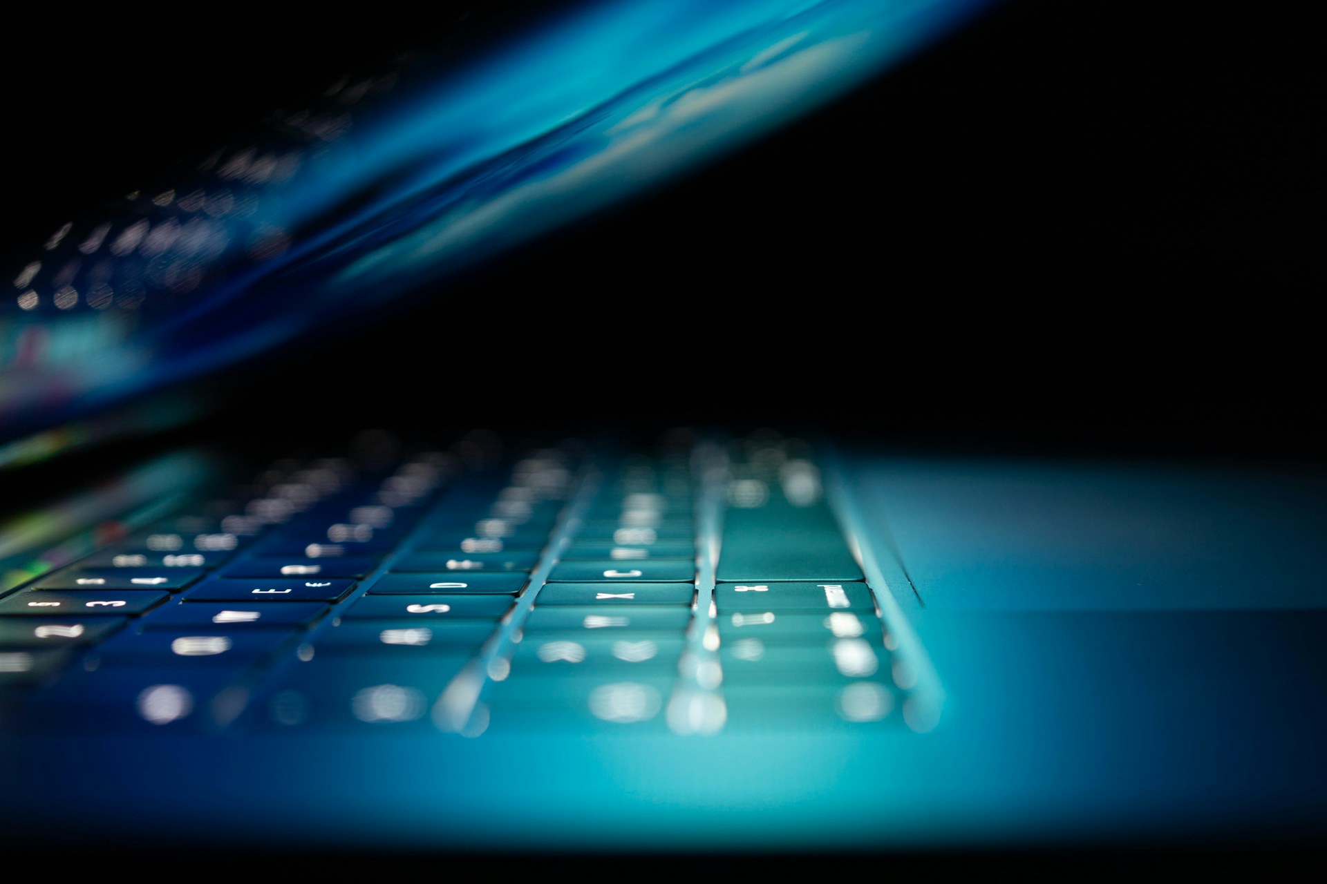 A laptop half-closed in a dim room, representing flexible online business training delivered outside normal business hours.